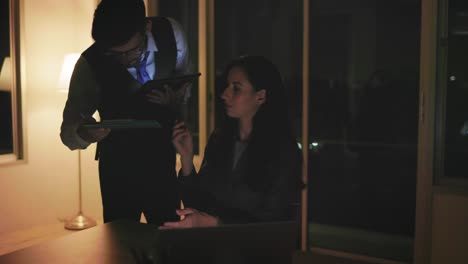 a beautiful caucasian secretary working in the office diligently at night offers documents to a handsome young executive to sign for approval. success and teamwork concept