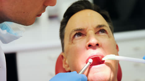 Dentists-examining-a-male-patient-with-tools