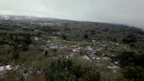 Snowy-village-with-vegetation-in-winter-under-a-cloudy-sky-in-Picornio,-a-village-in-Galicia