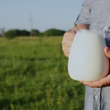 A-man-holds-a-jug-of-milk-in-a-green-meadow