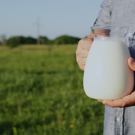 a man holds a jug of milk in a green meadow