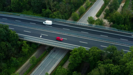 Car-driving-down-Italian-country-road,-passing-under-bridge