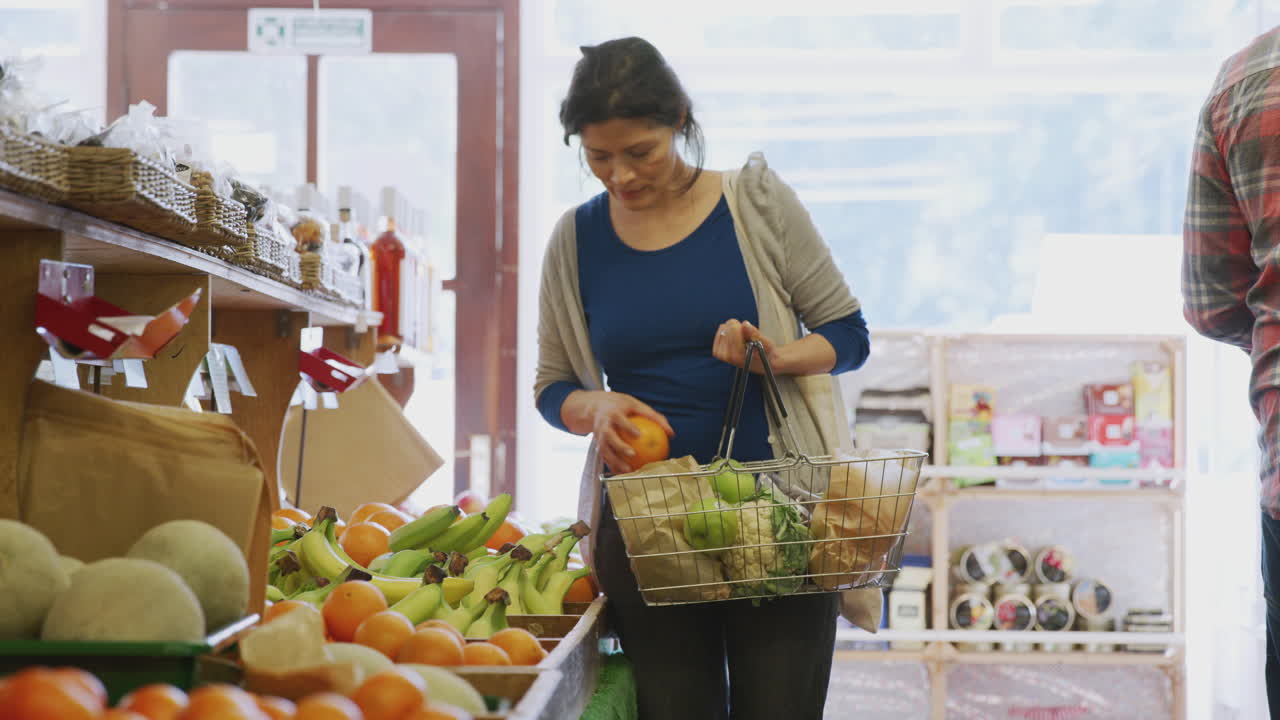 mujer madura cliente con cesta de compra de productos frescos en la tienda de la granja orgánica