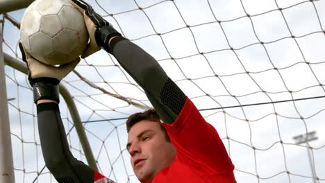 goalkeeper in red saving a goal during a game