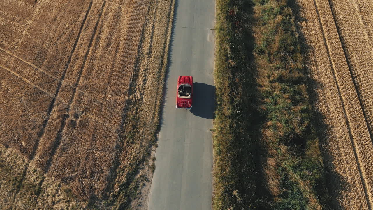una vista aérea de un coche descapotable de época roja conduciendo a través de campos agrícolas en alemania