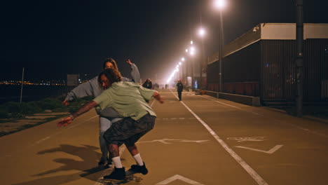 carefree friends enjoying skate ride night street. skater boy making kickflips