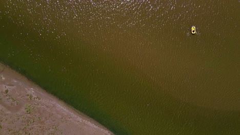 Drone-shot-of-small-boat-dingy-in-rippling-sea-water-and-beach