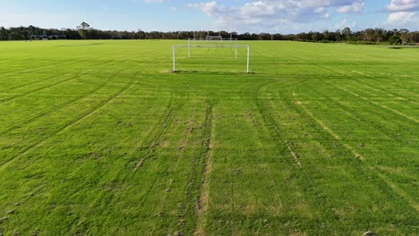 aerial view of a soccer field with goalposts, captured by a drone under clear skies, showcasing lush green grass