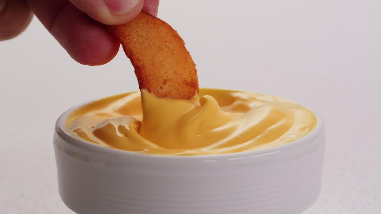 хрустящие картошка фри, погруженные в расплавленный сырный соус