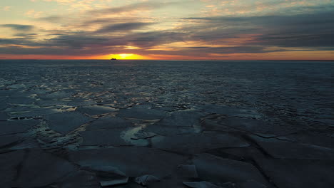 aerial backward movement shot over the melting arctic sea ice floes breaking up taking place in the sea