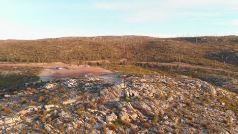 Young-couple-on-a-road-trip-standing-on-top-of-mountain-at-dusk