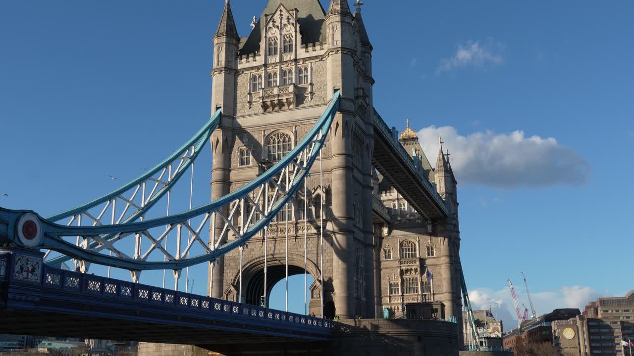 Nærbillede af Tower Bridge i London med stentårn og blå hængebrokonstruktion. Optaget om dagen under klar himmel, der fremhæver arkitektoniske detaljer.