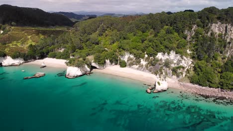 Cathedral-Cove,-The-Hoho-Rock-and-sandy-beach-through-cave-aerial-fly-sideway-shot