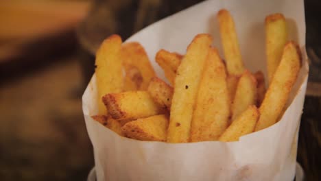 Homemade,-crispy-and-delicious-rustic-french-fries-displayed-in-a-metal-cup-with-paper-wrap---slider-motion,-close-up