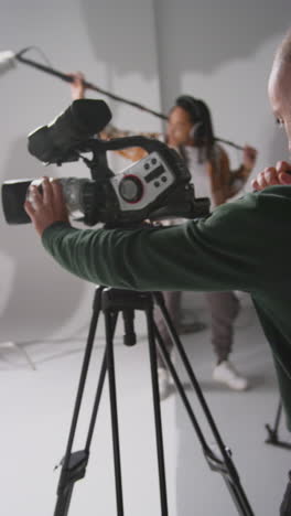 video vertical de un grabador de sonido masculino y un operador de cámara trabajando en un set de filmación filmando una película o video en el estudio 1