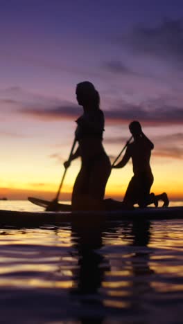 couple paddleboarding at sunset