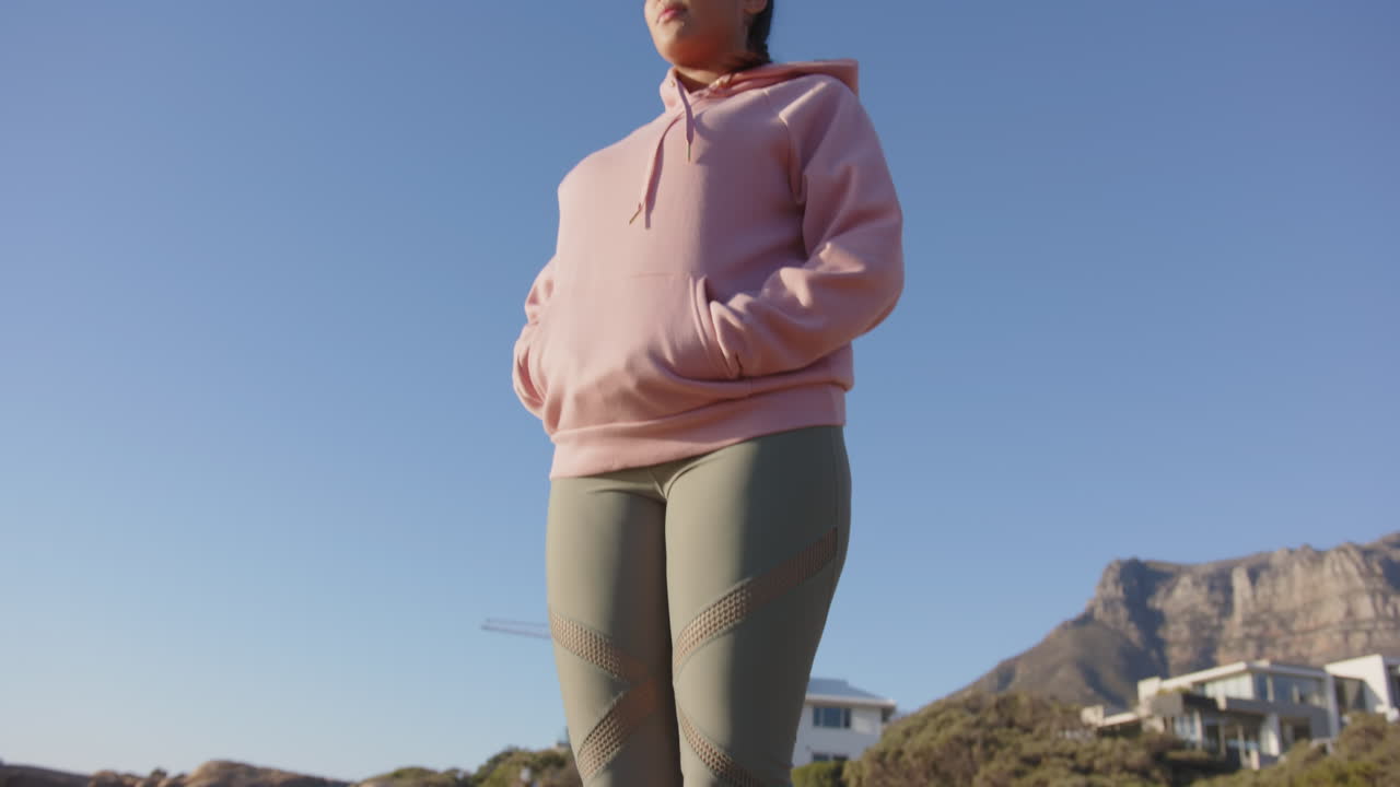 Stretching arms wide, asian woman in pink hoodie enjoying outdoor relaxation, copy space