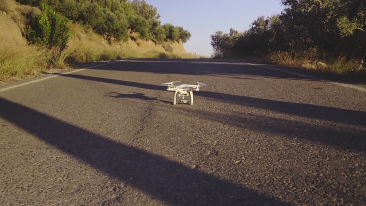 Drone bianco atterrato al centro della strada.