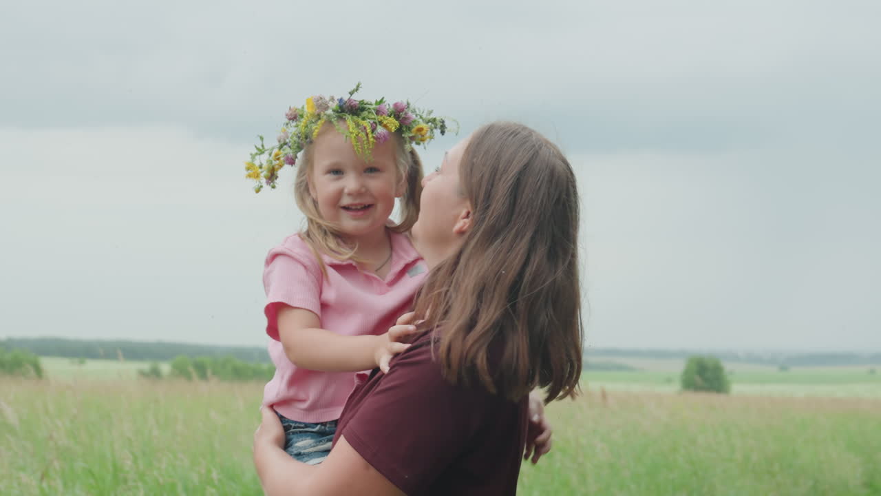 Mother and daughter share joyful moments, Cheerful mother and young girl basking in sunlight outdoors together, Joyful family bonding as mother lifts daughter amidst sunlit meadows and open fields