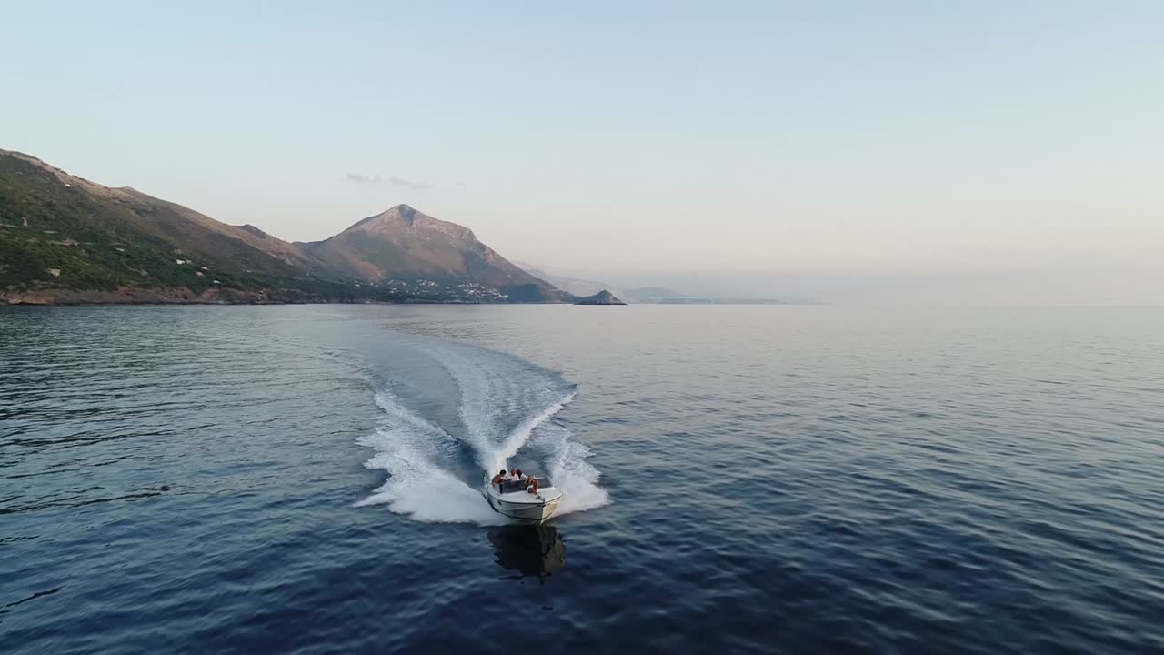 a boat is cruising through italian shores while a drone is filming its path