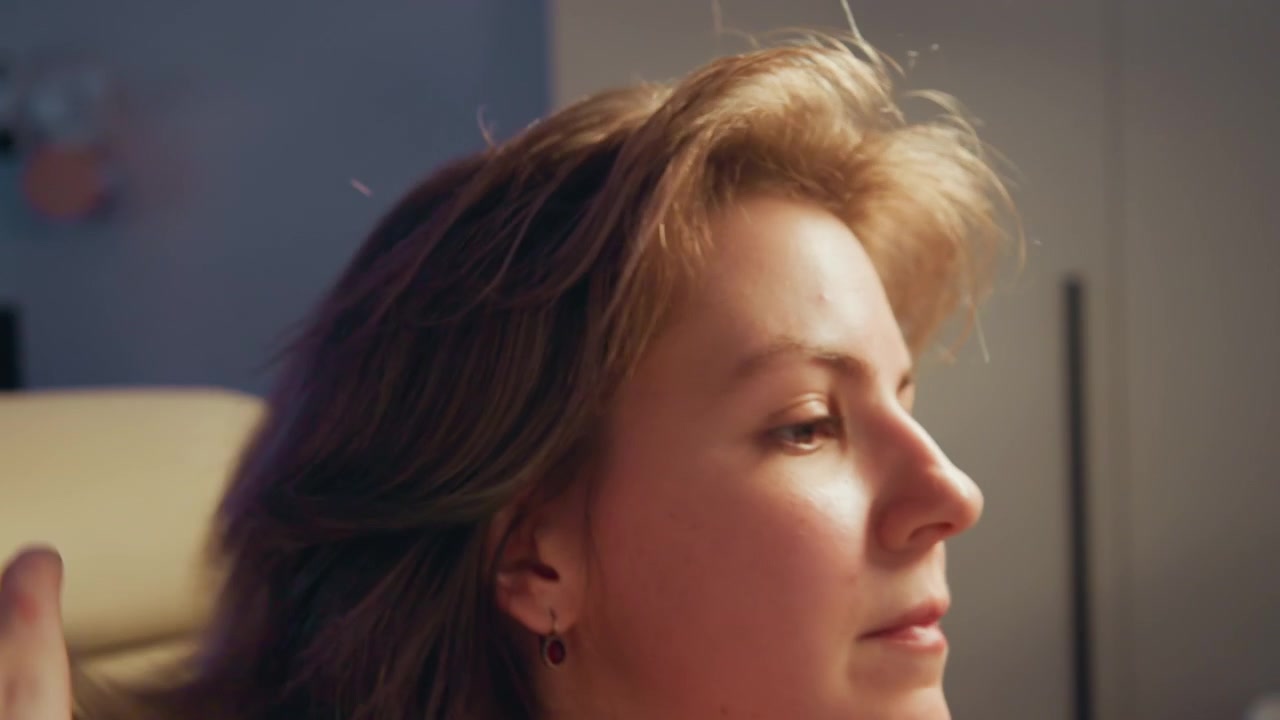 Close-up profile of young adult reclining in beige chair with eyes closed and head tilted back slightly, calm expression, warm indoor light, soft shadows, quiet indoor mood, with relaxation, rest