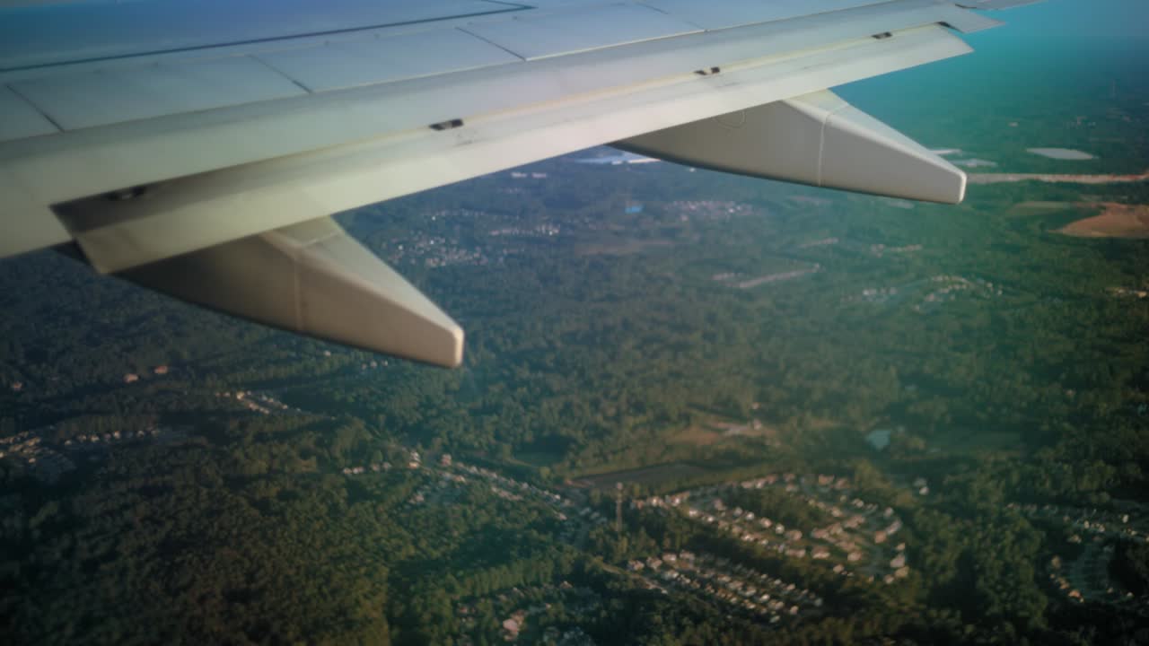 la vista desde detrás de un ala de avión mientras vuela sobre un área boscosa