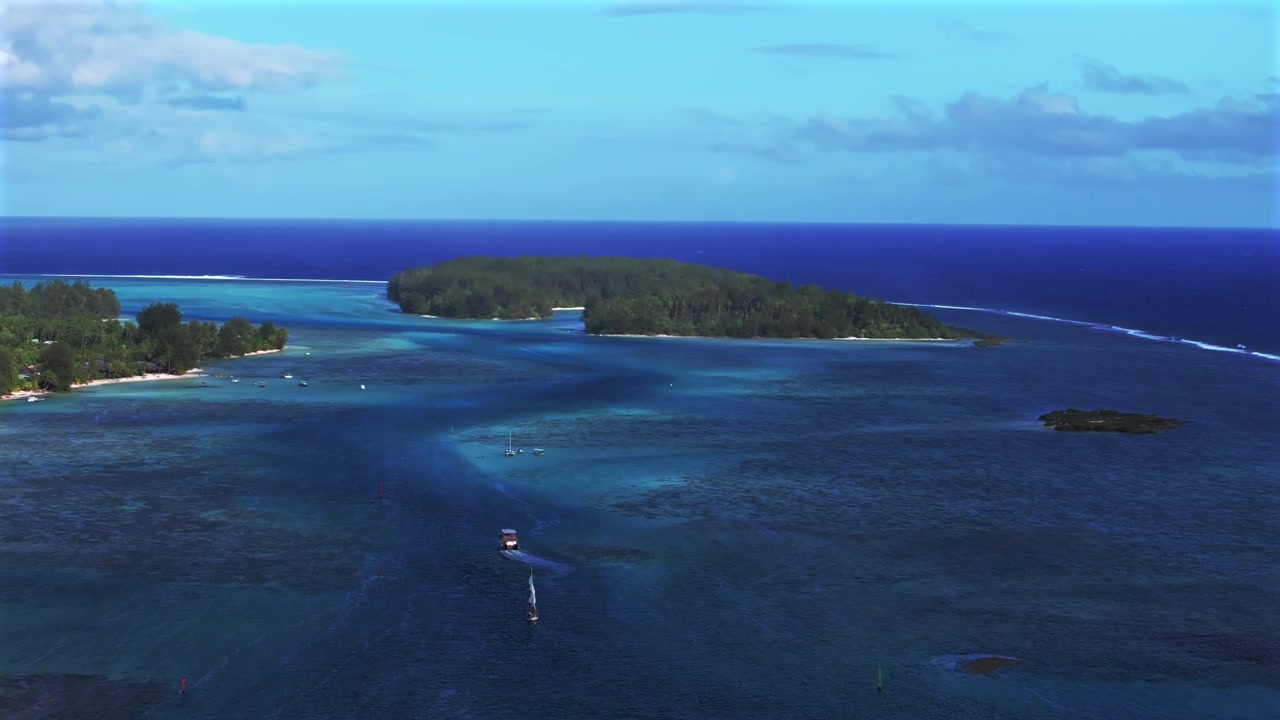 Luftfoto fra drone af Opunohu Bugt, Ta'ahiamanu Offentlige Strand og Cook's Bugt i Fransk Polynesien, med koralrevskanaler, sejlbåde og yachter nær øerne Bora Bora, Moorea og Tahiti. Optaget en solrig morgen med blå himmel og skyer, med en cirkulær bevægelse mod højre.
