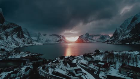 drone flight over reine, norway at sunset with blue dark clouds and winter ocean view - a surreal aerial footage
