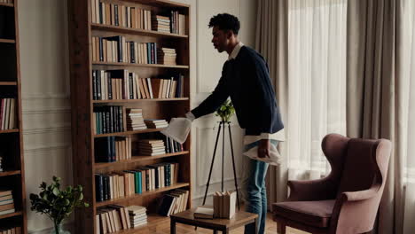 man cleaning bookshelf