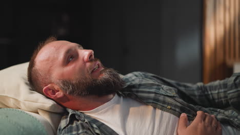 Bearded-man-takes-comfortable-pose-on-sofa-to-take-rest