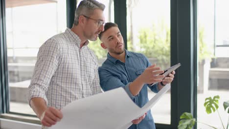 two diverse mele architects with digital tablet and a plan discussing at office