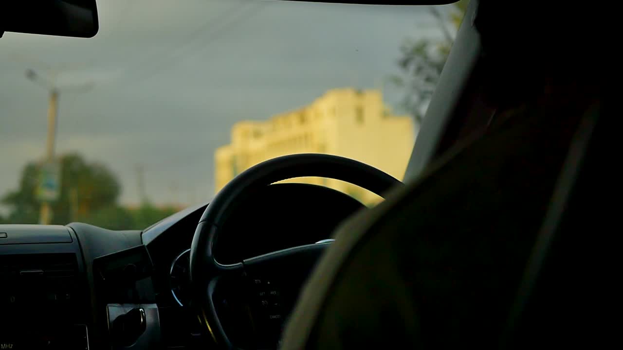 The driver's hands firmly grip the steering wheel as they drive down