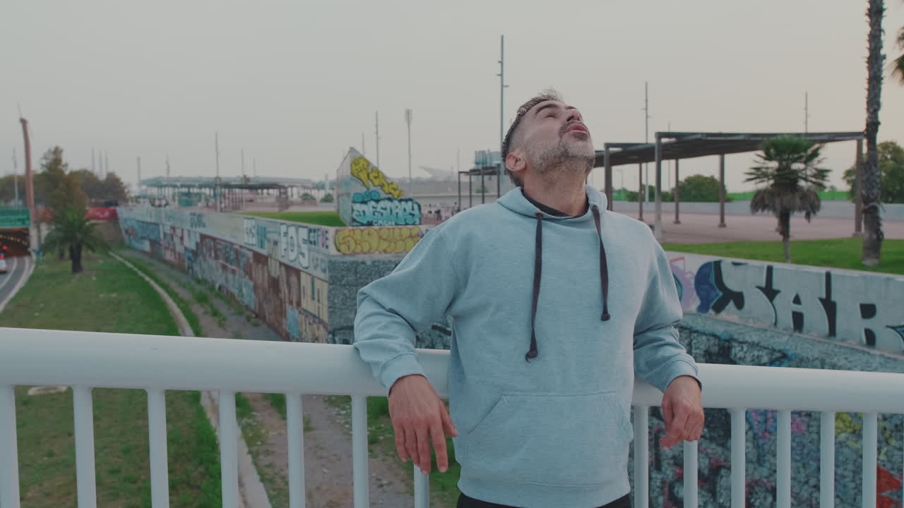 Uomo con felpa con cappuccio su un ponte