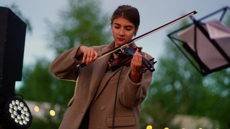 Giovane donna che suona il violino all'aperto a un evento serale