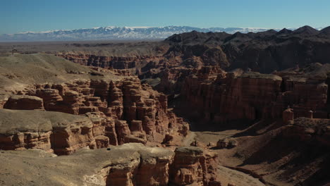 Aufschlussreiche-Filmische-Drohnenaufnahme-Der-Charyn-Schlucht-In-Kasachstan-Mit-Einer-Person,-Die-Auf-Den-Felsen-Steht