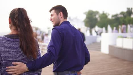 Close-up-back-view-of-young-beautiful-couple-walking-in-the-street-embracing-each-other.-Romantic-date