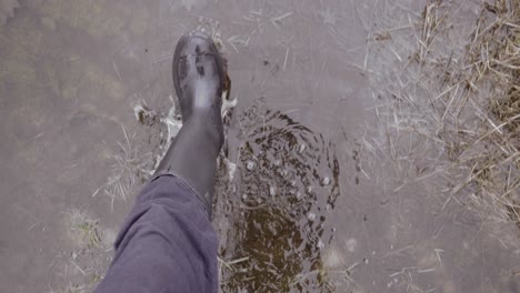 Man-in-wellies-walking-through-wet-marshland-puddles,-slow-motion-point-of-view