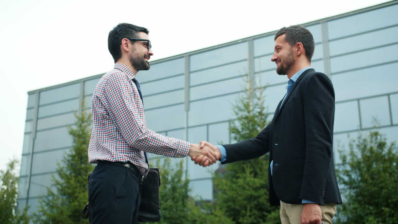 Businessmen shaking hands outside a modern building