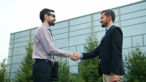 businessmen shaking hands outside a modern building