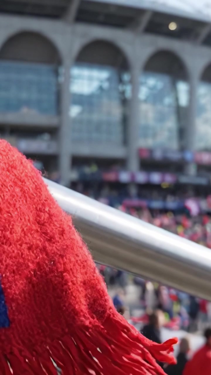 Atmosfera vibrante della folla a un grande evento sportivo con tifosi che indossano i colori della squadra ed energia entusiasta sugli spalti.