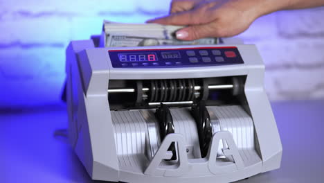 electronic equipment for financial operations in bank. woman's hand putting paper money into a counting machine.