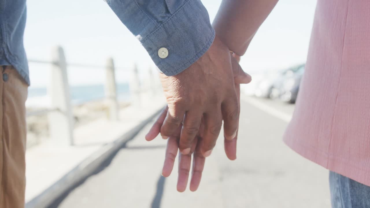 해변의 산책로에서 손을 잡고 있는 노인 아프리카계 미국인 부부의 클로즈업, 슬로우 모션