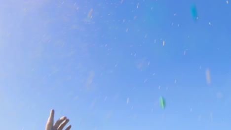 low angle shot of multi-ethnic group of diverse young people dancing and throwing colorful powder in the air and raising hands in celebration of holi festival. they have enormous fun on this sunny day.