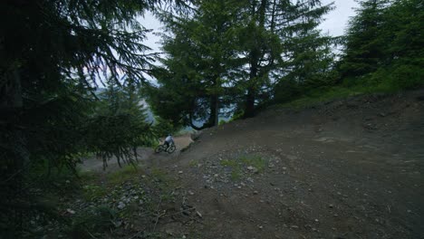 Ciclista-De-Montaña-Corta-Una-Esquina-Y-Da-Un-Salto-En-Un-Bosque-Oscuro