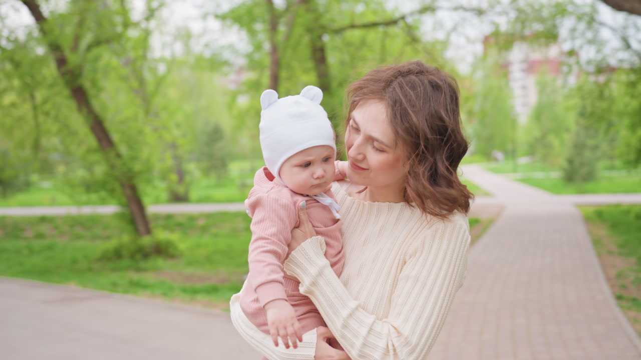 Outdoor Exchange Between Generations, Mother Receives Infant From Caring Grandmother Outside, Multigenerational Family Exchanges Affectionate Care Outdoors Near Stroller On Leafy Path