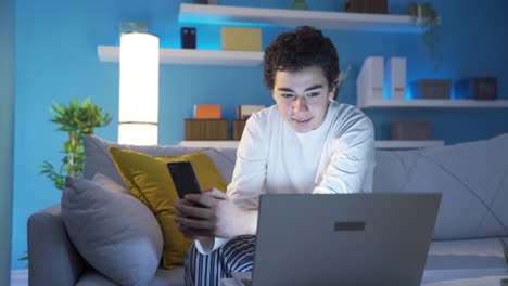 cute and happy boy looking at his smartphone at home, texting, using social media.