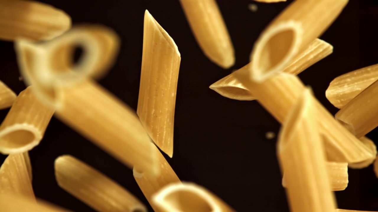 Rohe Penne-Nudeln fallen in Zeitlupe