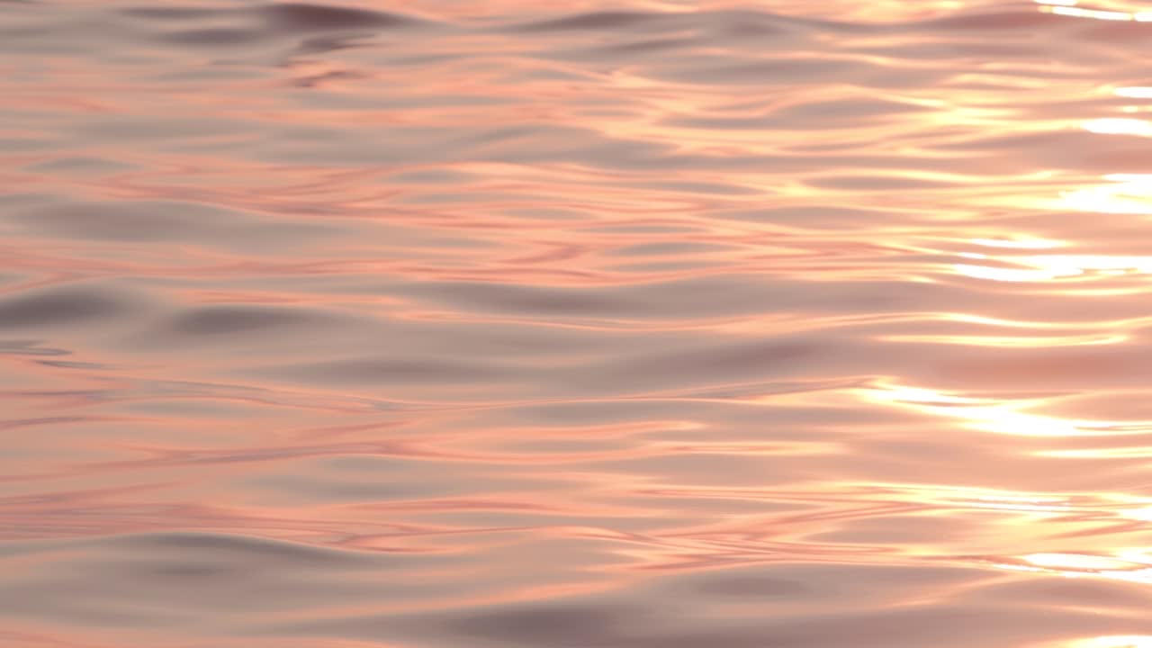 Orange sunlight glimmering on slow moving smooth ripples and waves