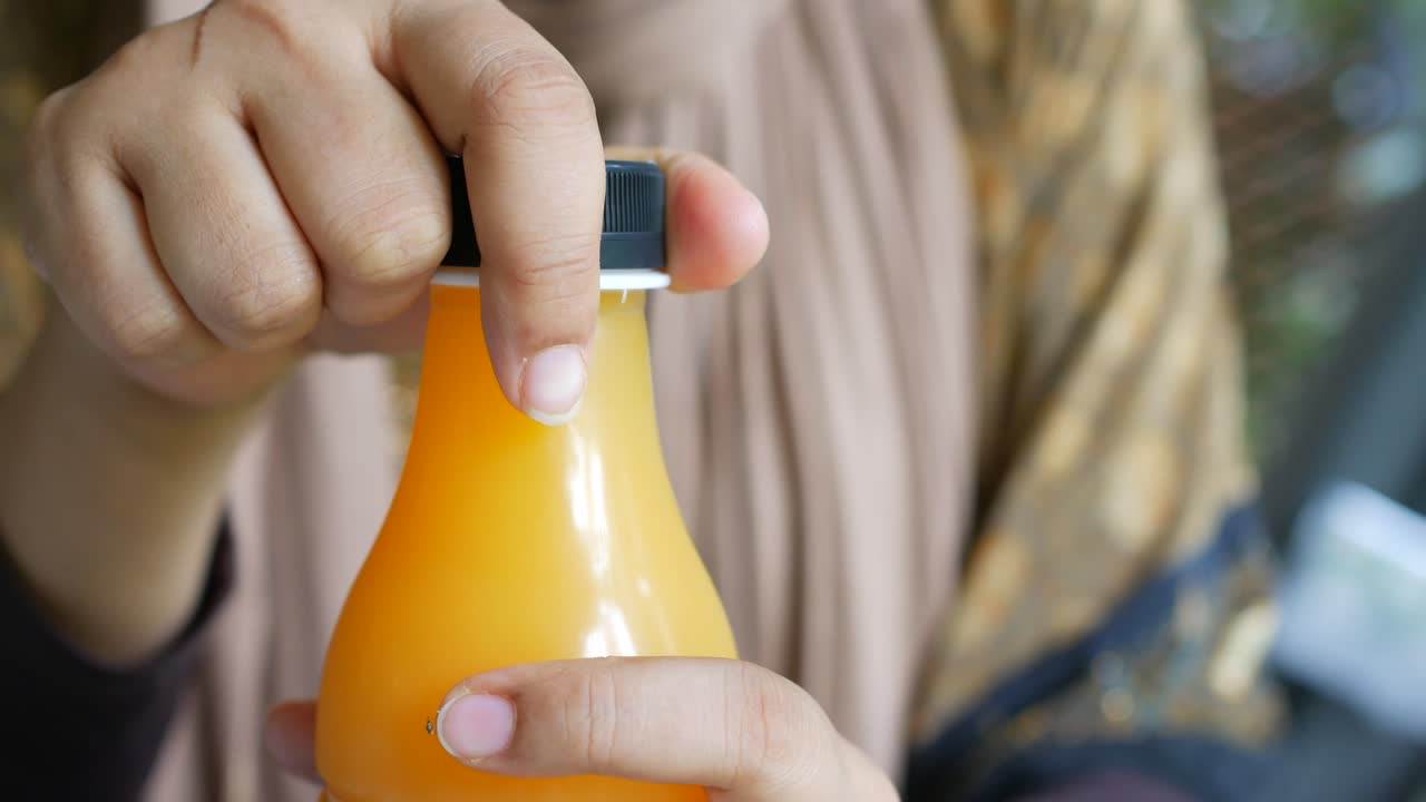 mujer abriendo una botella de jugo de naranja