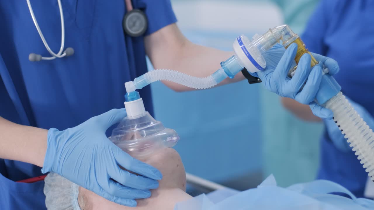 The anesthesiologist, in medical gloves, prepares female patient for surgery, puts her into anesthesia, regulates oxygen mask. surgery. anesthesia